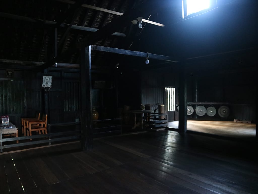 Kondisi ruang tengah Rumah Betang yang dipenuhi perabotan kuno seperti belanga, tombak, alat musik tradisional, serta meriam tembaga